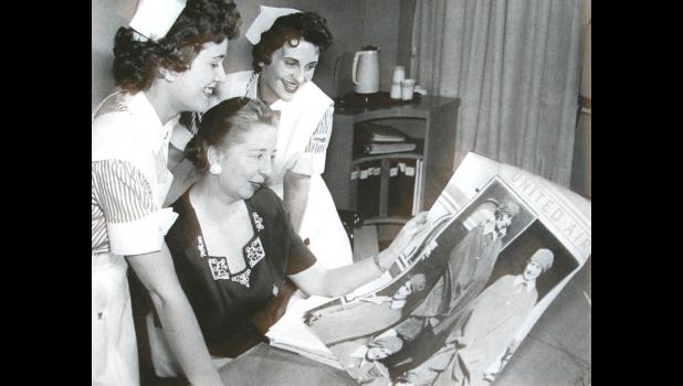 Ellen Church is shown looking over a magazine with a few nurses.