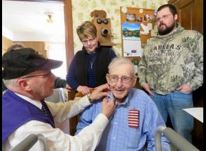 Friend and fellow veteran Mark Grinhaug pins the Iowa Hospice Veteran Partnership pin on Ron Hovey.